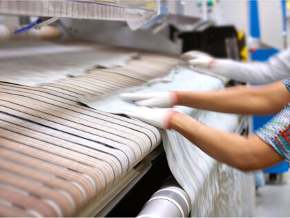 K-Bro staff feeding linen into a machine