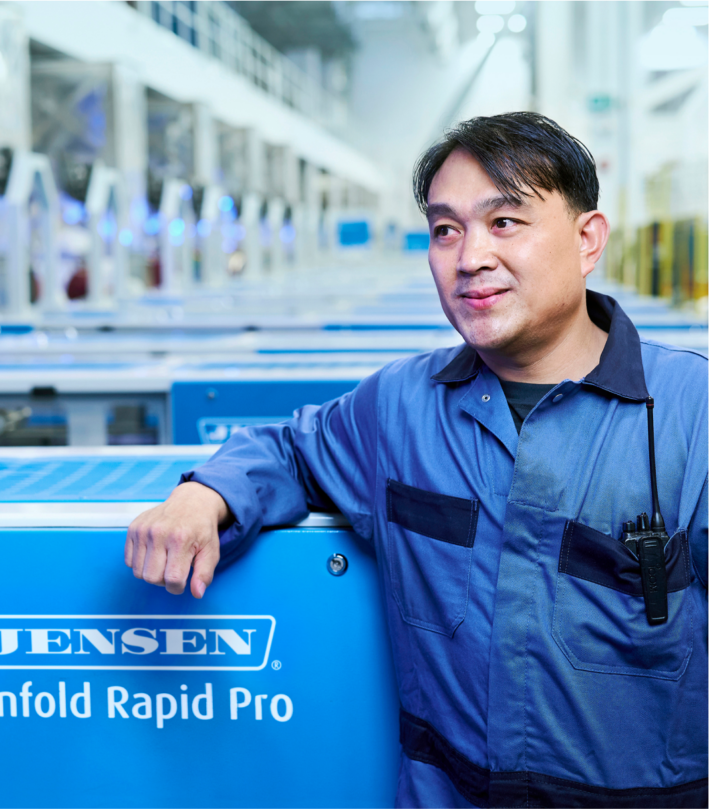K-Bro Linen Technician in front of a commercial linen machine